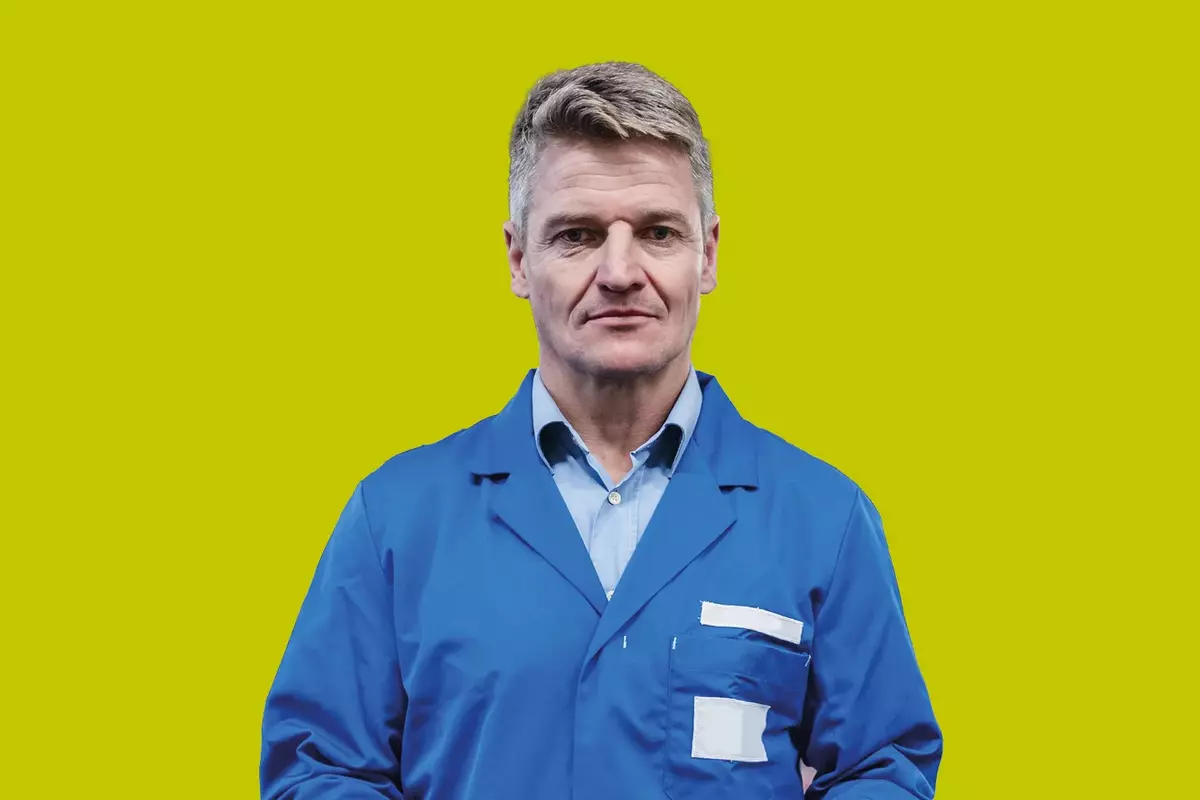 Mann im Blaumann vor gelbem Hintergrund