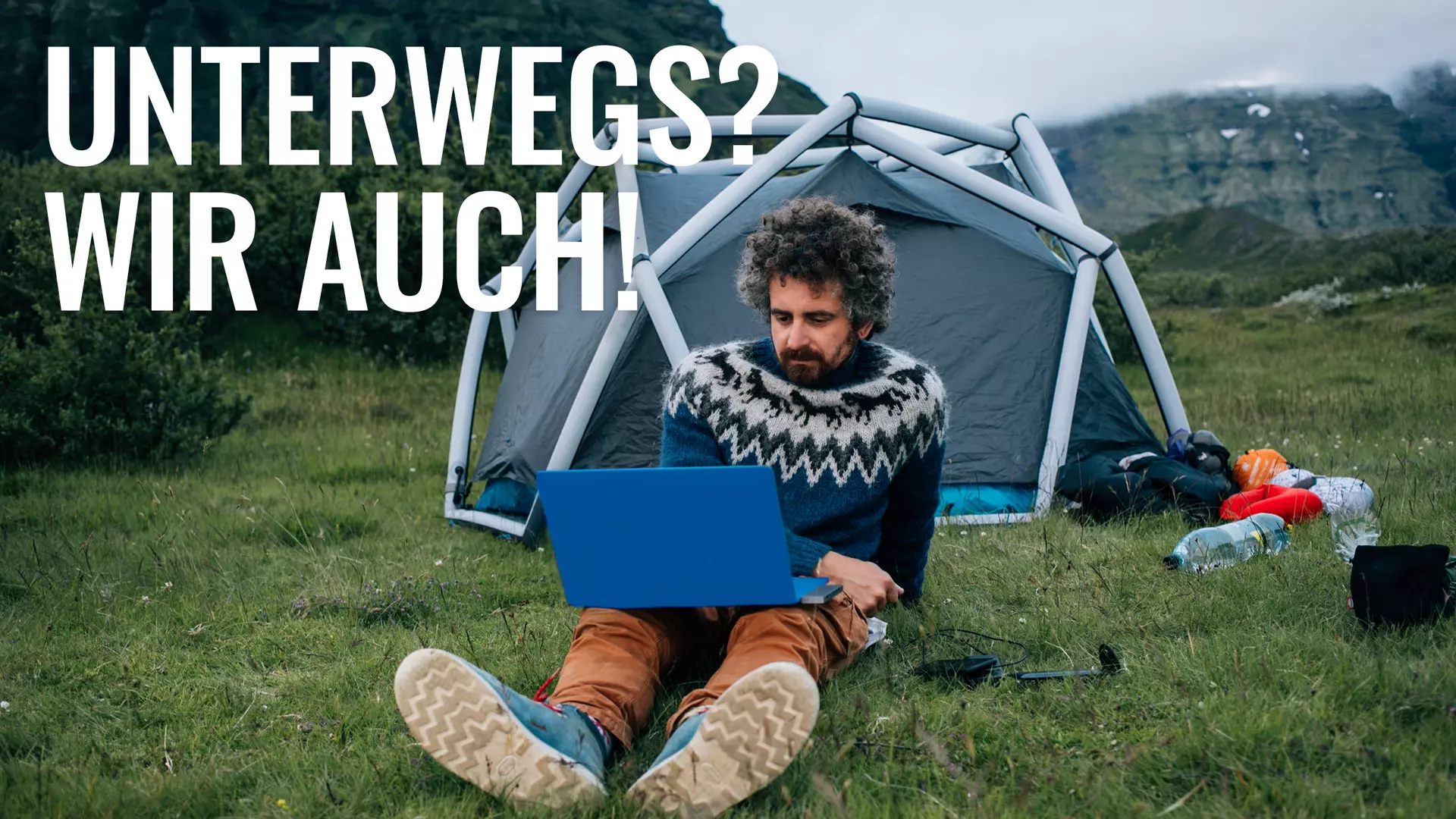 Unterwegs? Wir auch. Mann mit Laptop vor Zelt in den Bergen