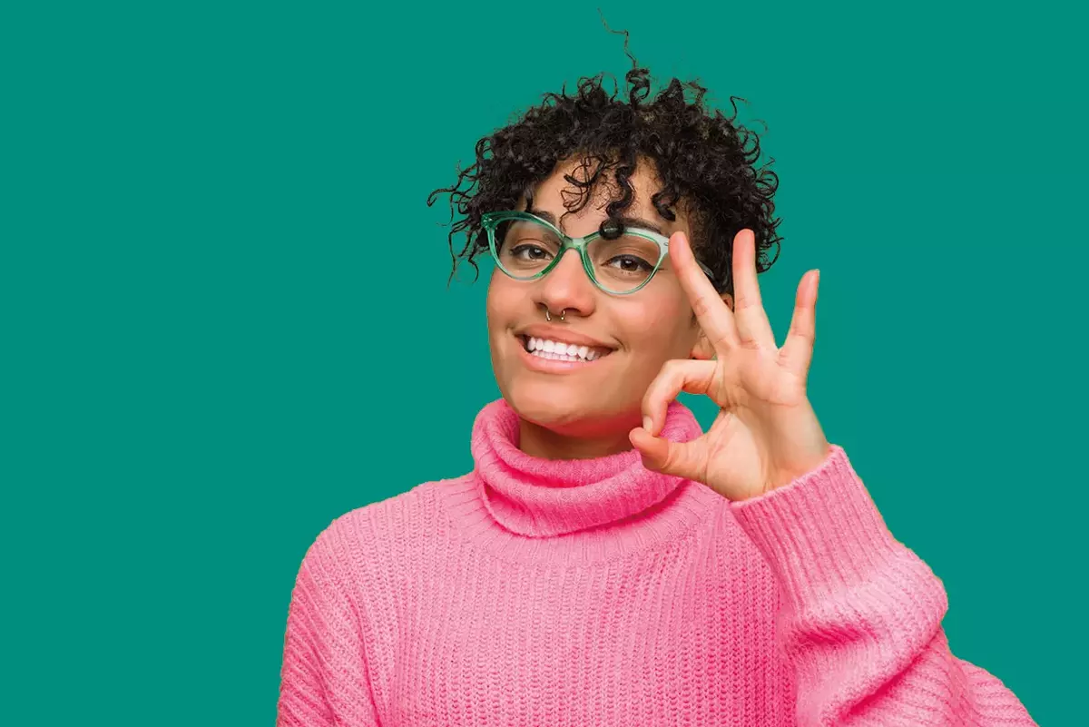 Junge Frau mit pinkem Shirt und Brille vor grünem Hintergrund