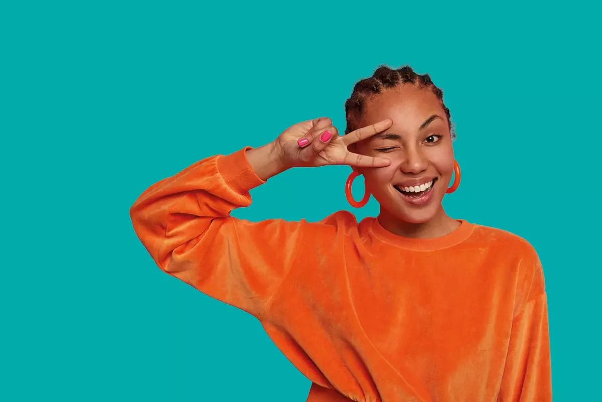 Frau im orangenem Pullover vor grünem Hintergrund