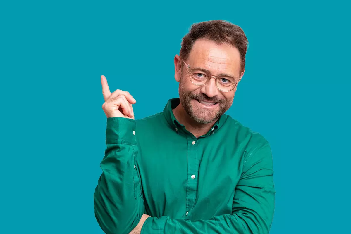 Mann zeigt, mit grünem Hemd vor blauem Hintergrund
