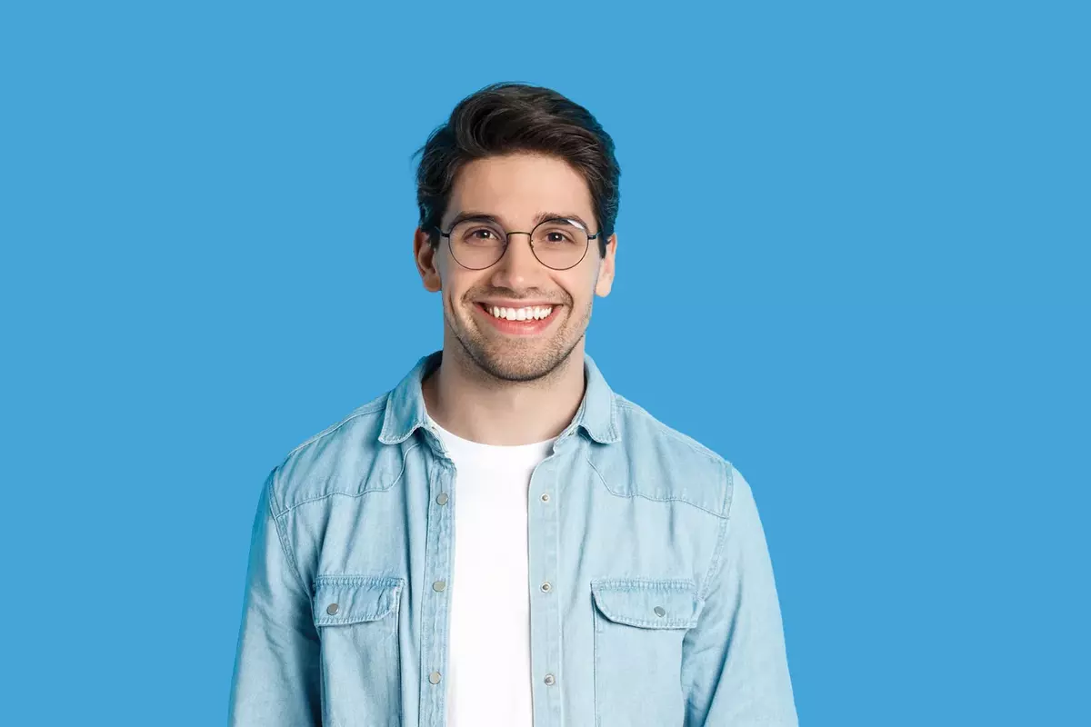 Junger Mann mit Brille vor hellblauem Hintergrund