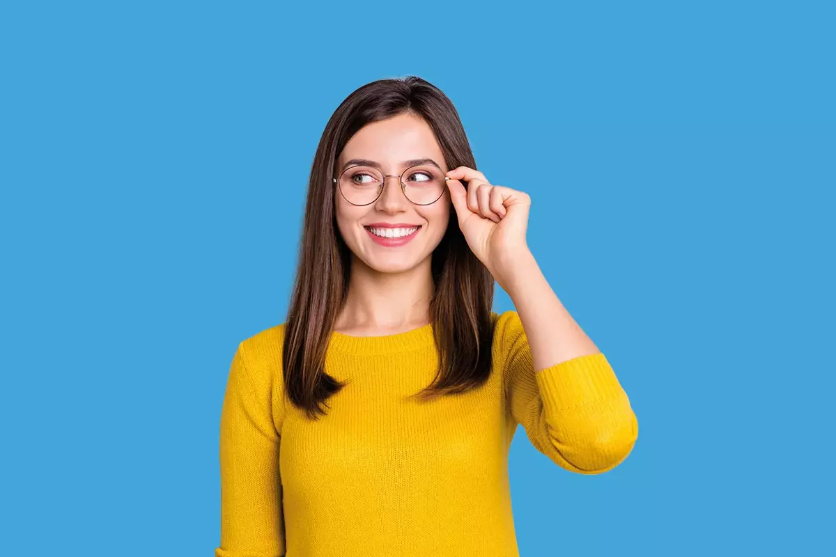 Frau mit gelbem Shirt und Brille vor hellblauem Hintergrund