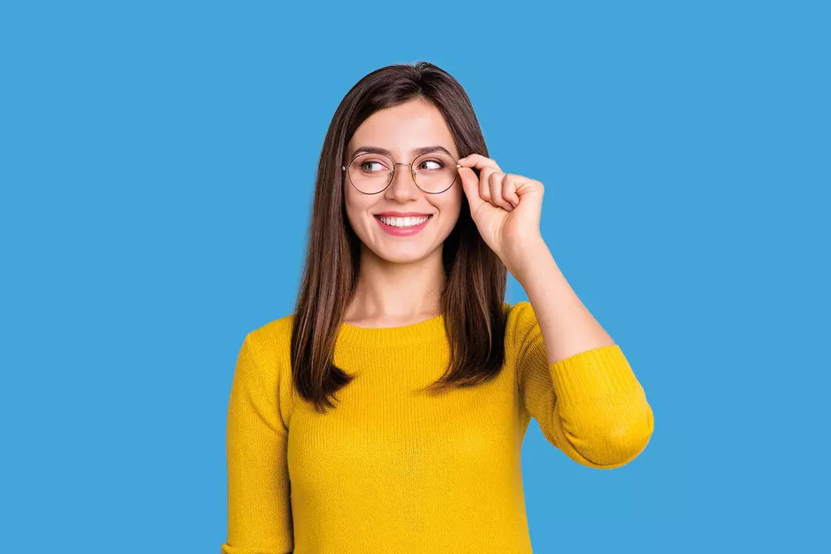 Frau mit gelbem Shirt und Brille vor hellblauem Hintergrund